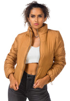 Woman wearing a tan jacket over a white top and black pants on a white background