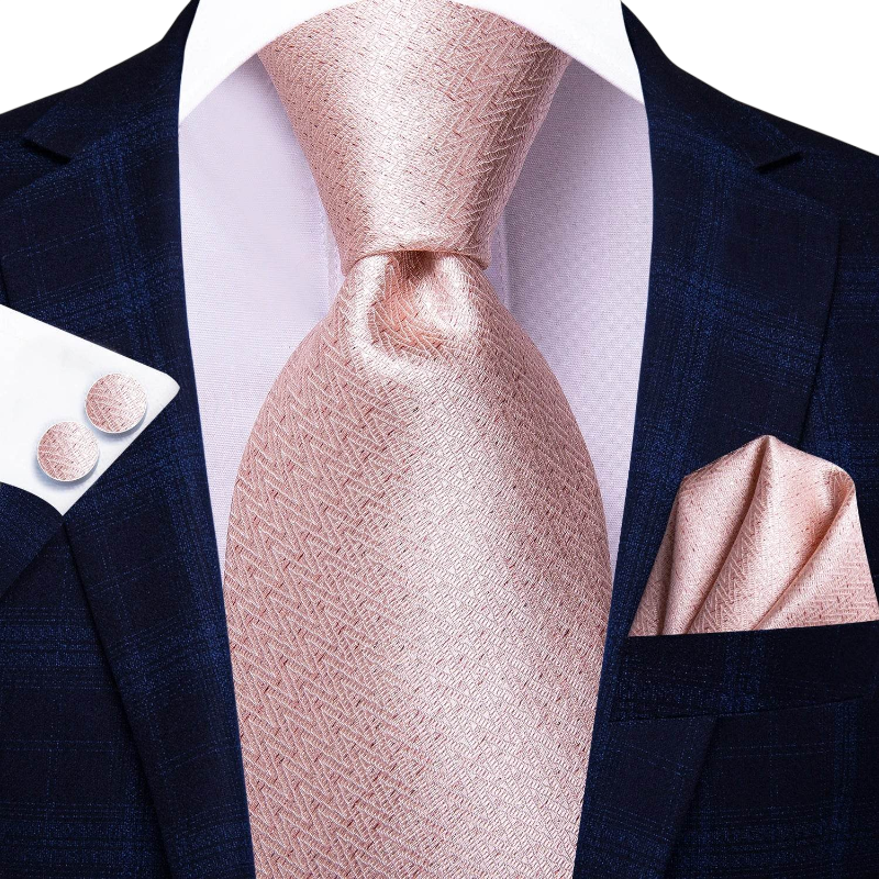 Navy suit with a pink tie, pocket square, and cufflinks on a white background
